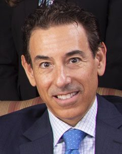 A man in a suit and tie smiling for the camera.