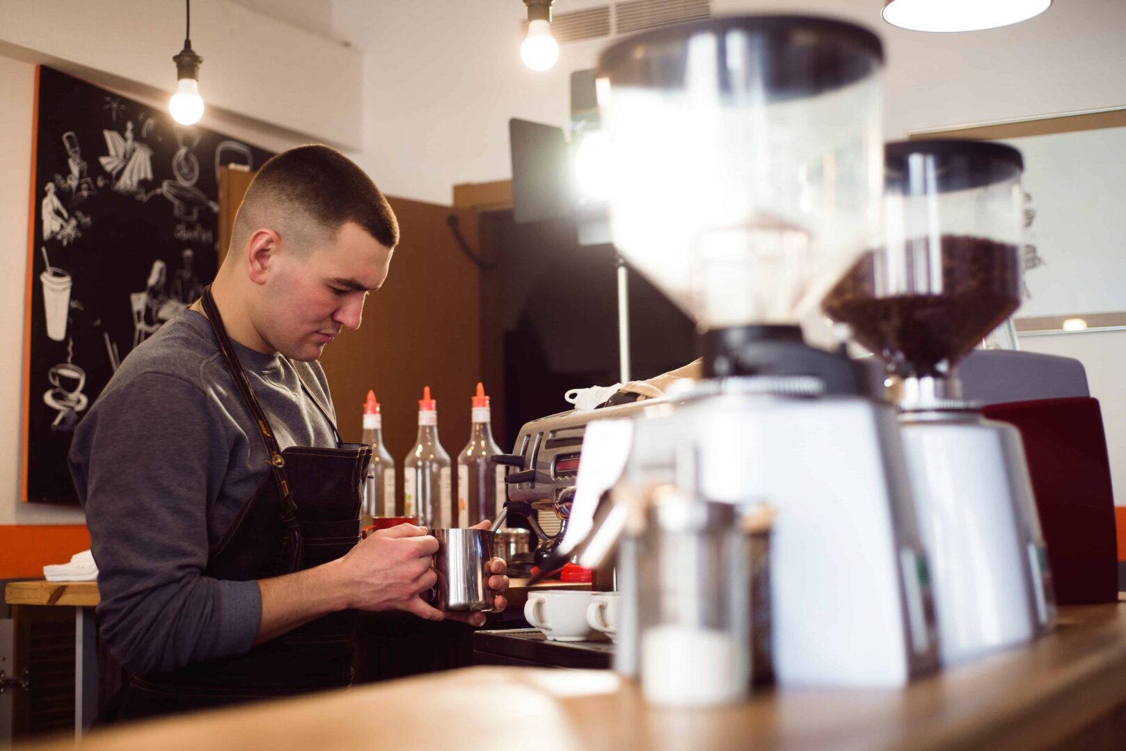 A man working in a coffee shop with several machines.