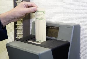 A worker is punching his time card with the automatic clock