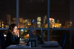 Pretty business woman working alone in dark office